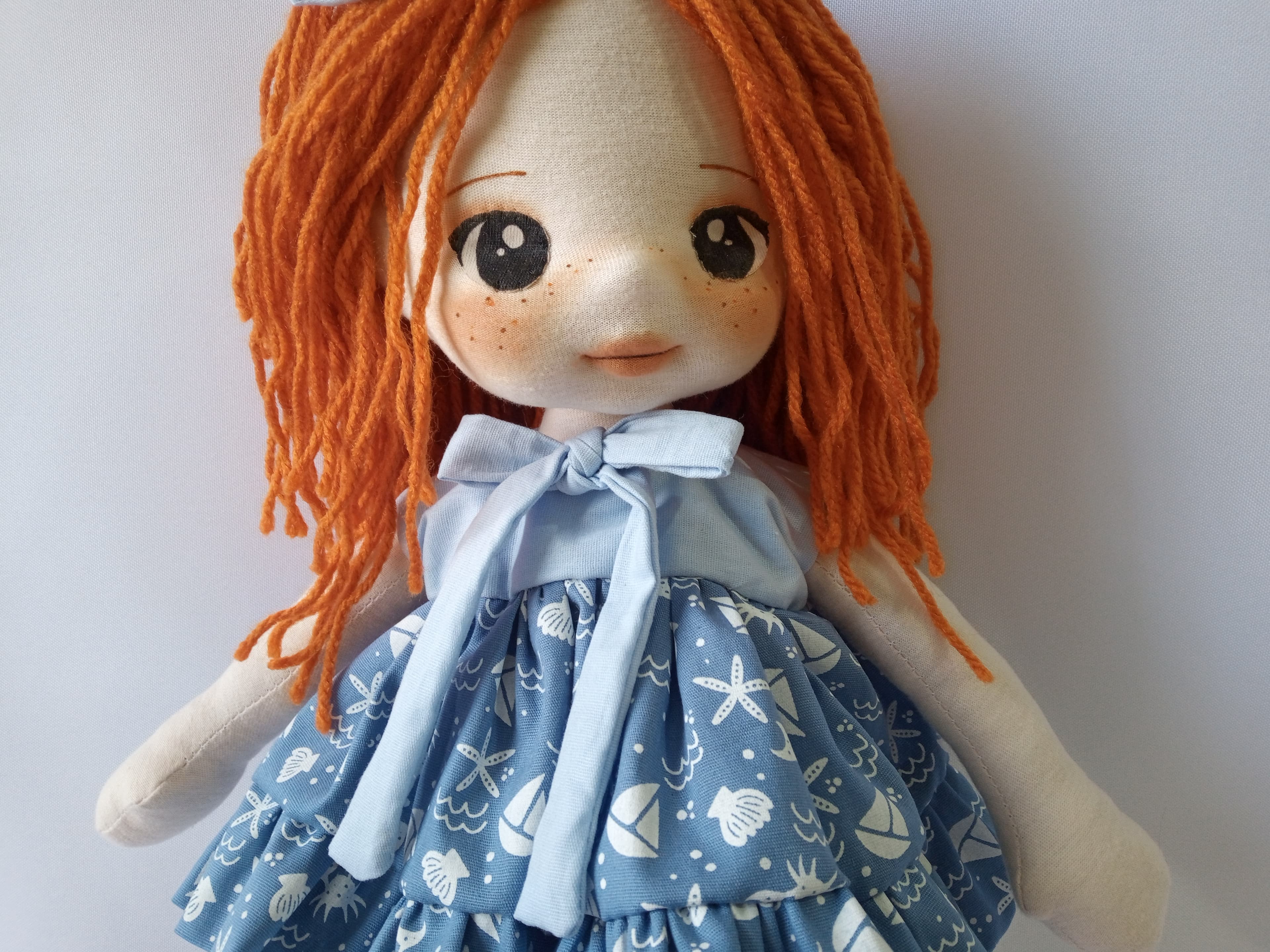 Selfe de boneca de pano ruiva com vestido azul, desenho marinho.